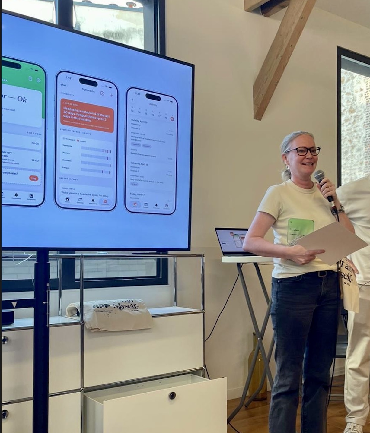 Nina Kolari presenting a mobile app on stage at a hackathon